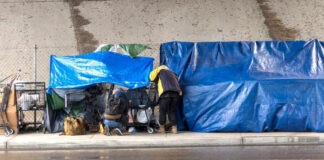 Two people with tarps and shopping carts outdoors