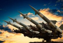 Cruise missile launcher with missiles pointed upwards against a sunset sky