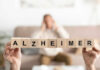 Wooden blocks spelling Alzheimer with blurred person behind