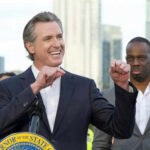 Gavin Newsom’s “Handsome” Debate Erupts Person speaking at podium with others in background