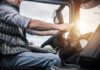 Trucking Industry Crisis—Are Your Roads Safe? A truck driver gripping the steering wheel inside a vehicle cabin
