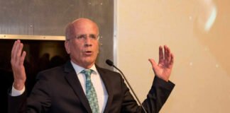 A man in a suit speaking passionately at a podium