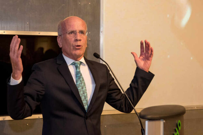 A man in a suit speaking passionately at a podium