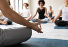 Participants in a yoga class practicing meditation on mats