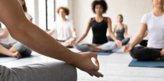 Participants in a yoga class practicing meditation on mats