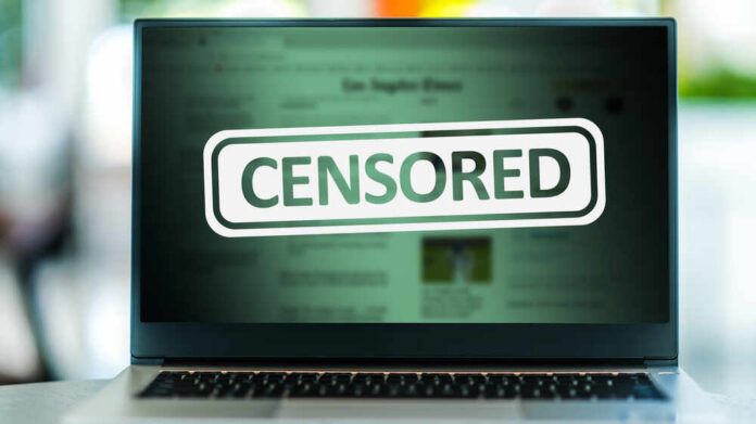 shutterstock_1983398327.jpg A laptop screen displaying a 'CENSORED' label over blurred content