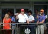 Group of people at a golf event with a political figure in a red hat