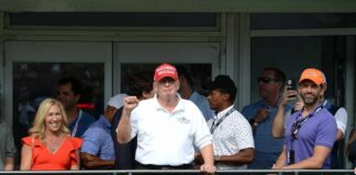 Group of people at a golf event with a political figure in a red hat