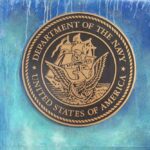 Bronze seal of the Department of the Navy against a blue background