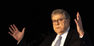 A man in a suit gesturing while speaking at a podium