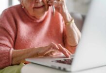 Urgent Bank Alerts Prey on Seniors Elderly woman talking on the phone while using a laptop
