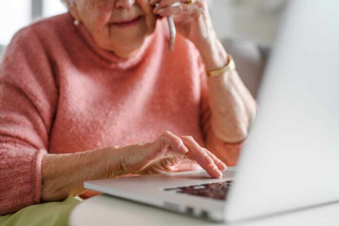 shutterstock_2466940953.jpg Elderly woman talking on the phone while using a laptop