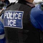 Journalist Arrest Sparks Constitutional Showdown Close-up of a police officer's vest with 'POLICE ICE' label
