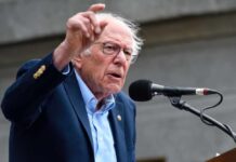A man passionately speaking at a microphone during a public rally