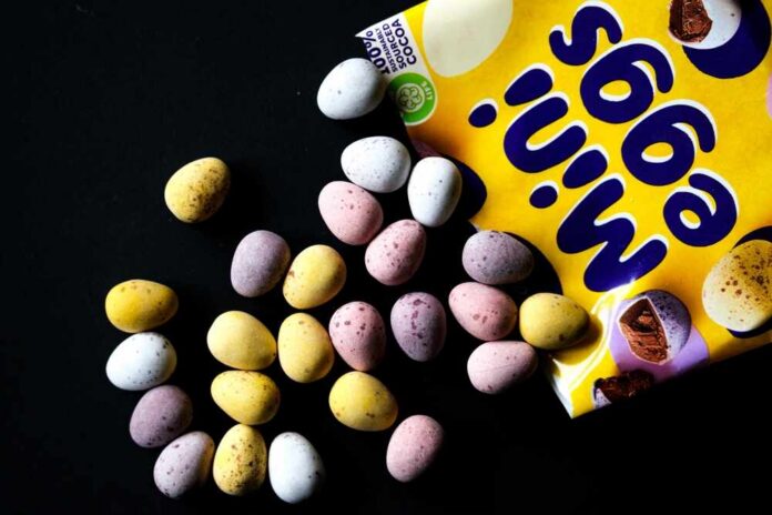 Colorful chocolate eggs scattered around a yellow packaging