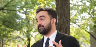 A man in a suit gesturing while speaking outdoors