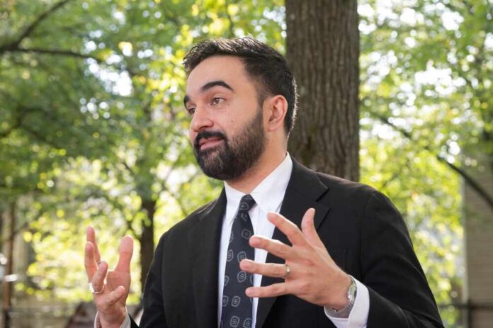 A man in a suit gesturing while speaking outdoors