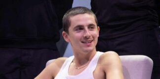 A young man in a tank top smiling while seated in an interview setting
