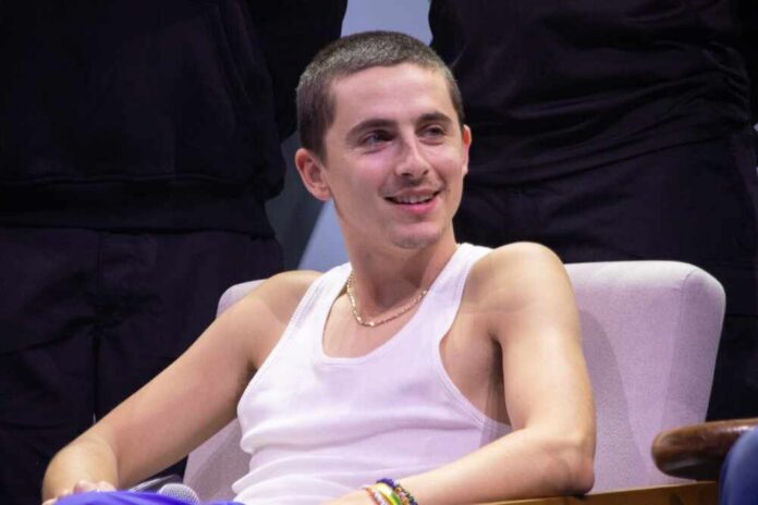 A young man in a tank top smiling while seated in an interview setting