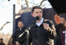 A speaker addressing an audience at an outdoor event with a microphone