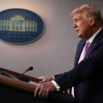 Person speaking at a podium with White House emblem