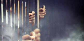 Hands gripping prison bars in smoky atmosphere