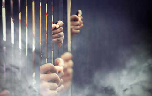 Hands gripping prison bars in smoky atmosphere