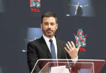 A man in a suit speaking at a podium during an event at TCL Chinese Theatre