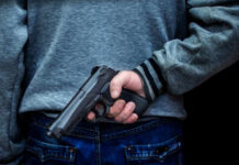 Stunning Heroism: Principal Tackles Armed Intruder Person holding a handgun behind their back