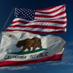 American and California flags waving against a blue sky