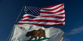 American and California flags waving against a blue sky