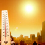 Thermometer displaying high temperature against a sunset city skyline