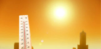 Thermometer displaying high temperature against a sunset city skyline