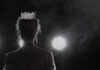 Silhouette of a person wearing a crown against a dark background with dramatic lighting