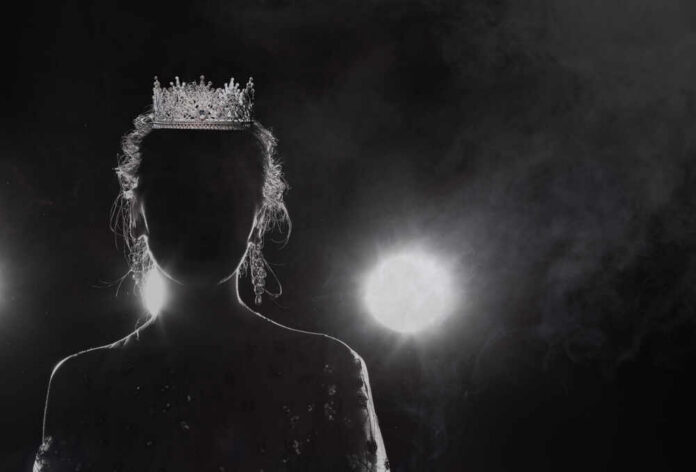 Silhouette of a person wearing a crown against a dark background with dramatic lighting