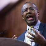 A man in a suit passionately speaking at a podium