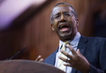 A man in a suit passionately speaking at a podium