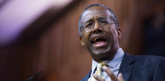 A man in a suit passionately speaking at a podium