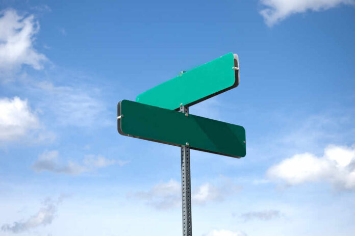 Two blank green street signs against a blue sky