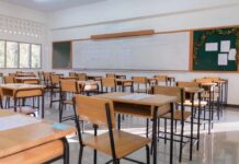 An empty classroom with wooden desks and a chalkboard