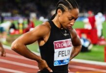 An athlete in a black uniform looking down with a focused expression