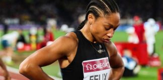 An athlete in a black uniform looking down with a focused expression