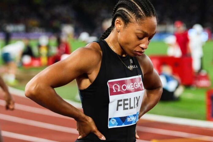 An athlete in a black uniform looking down with a focused expression
