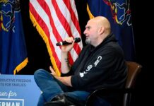 Speaker at a political event discussing issues with American flags in the background