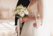 Bride holding a bouquet with groom's hand on her waist