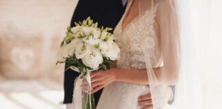 Bride holding a bouquet with groom's hand on her waist
