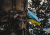 A damaged building with a Ukrainian flag in the background