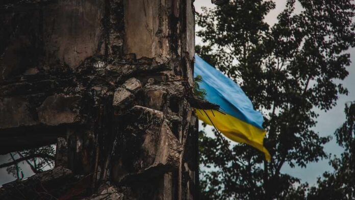A damaged building with a Ukrainian flag in the background