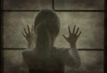 A silhouette of a child with hands pressed against a window