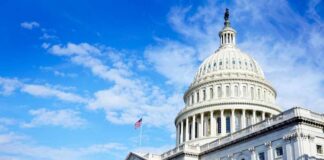The U.S. Capitol building with an American flag flying under a blue sky